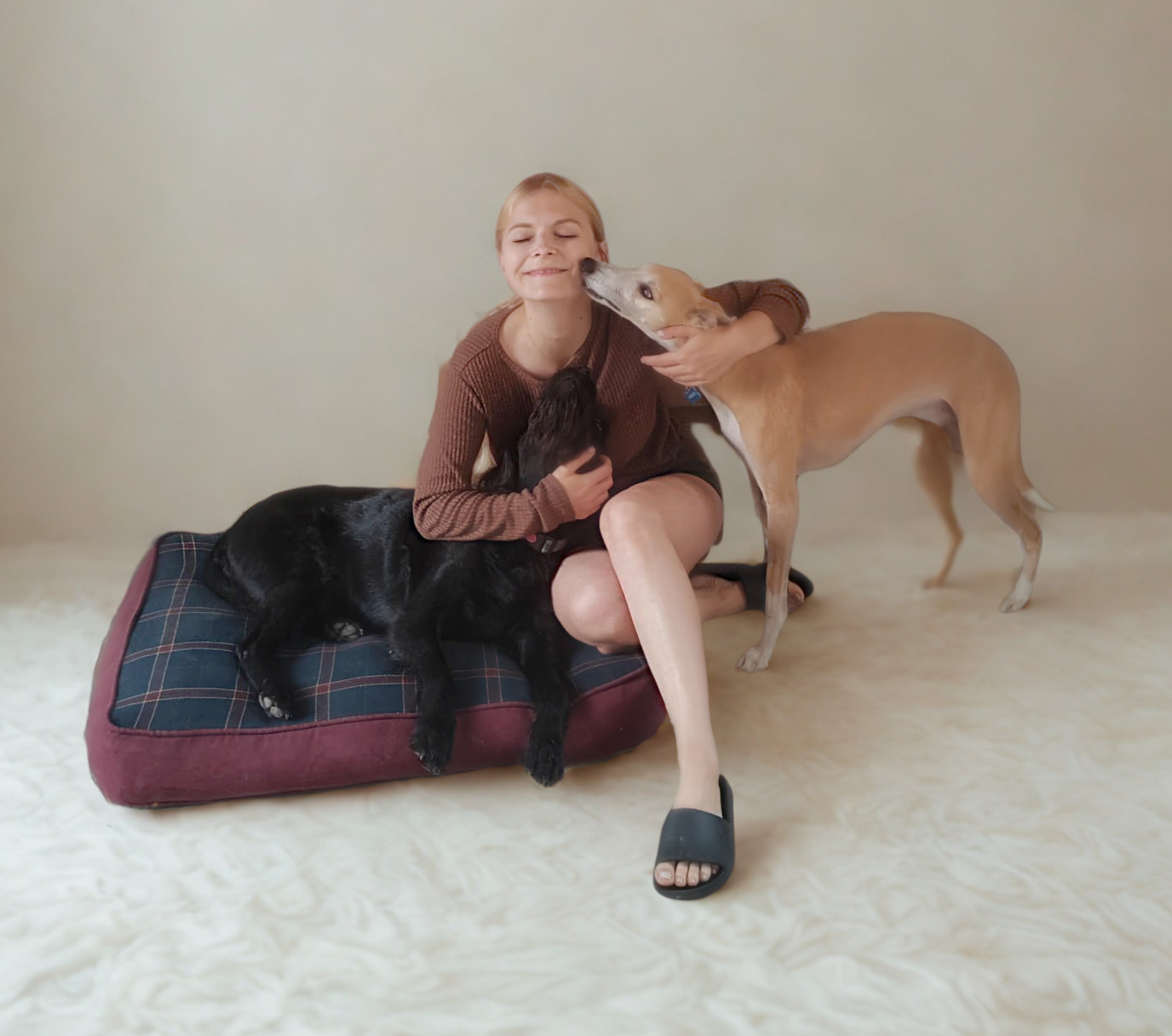 Pola sitting with two dogs - a black dog and a light-colored dog showing affection
